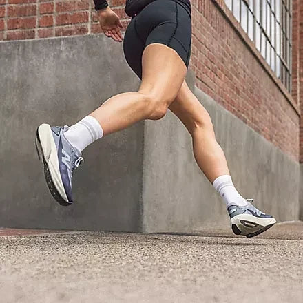 Runner wearing light-coloured shoes beside a brick wall