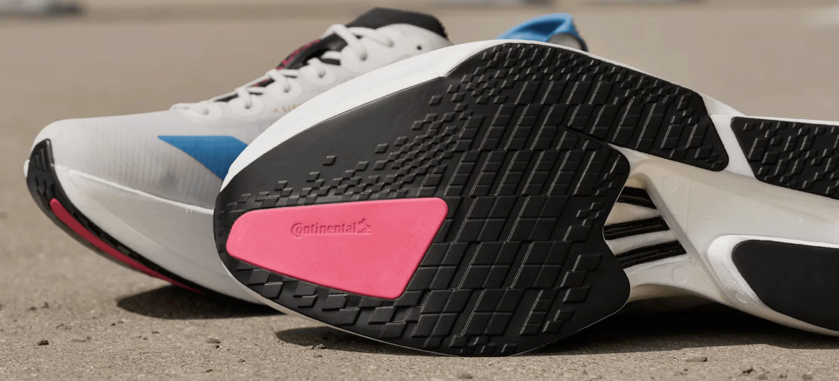 White running shoes showing a black outsole with pink detailing