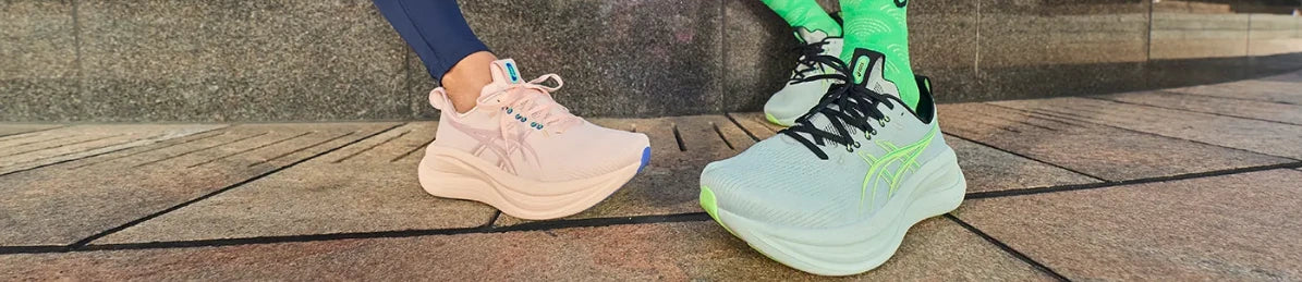 Pink and pale green ASICS running shoes being worn outdoors