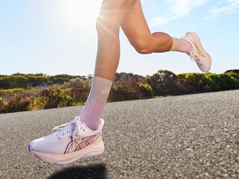 Runner wearing pale pink ASICS shoes on a road