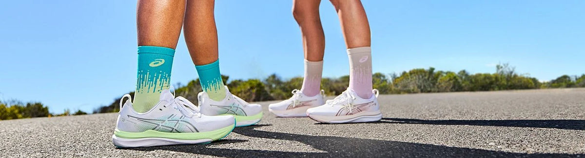 Two runners wearing pale green and pink ASICS shoes