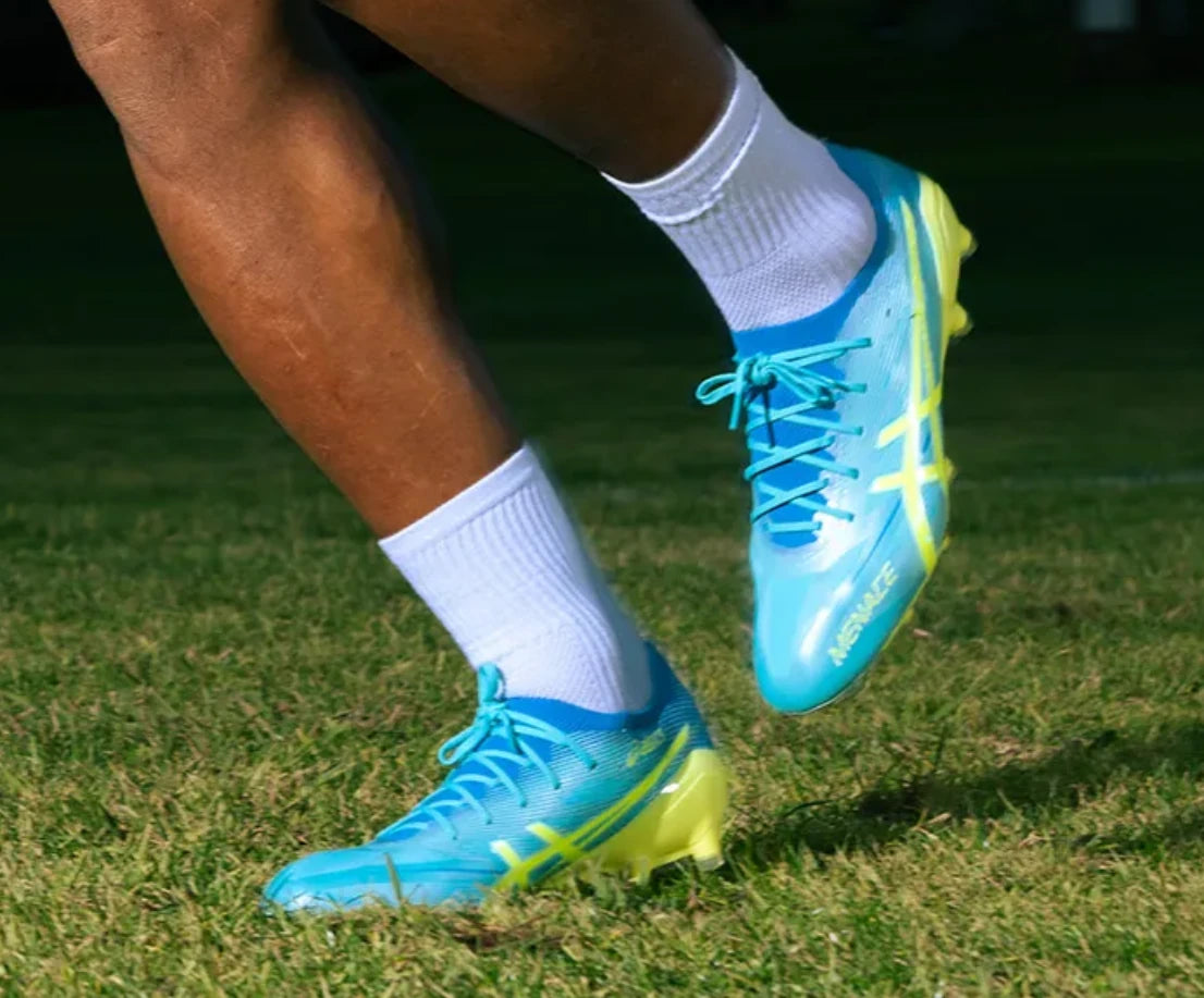 Player wearing bright blue rugby boots on grass