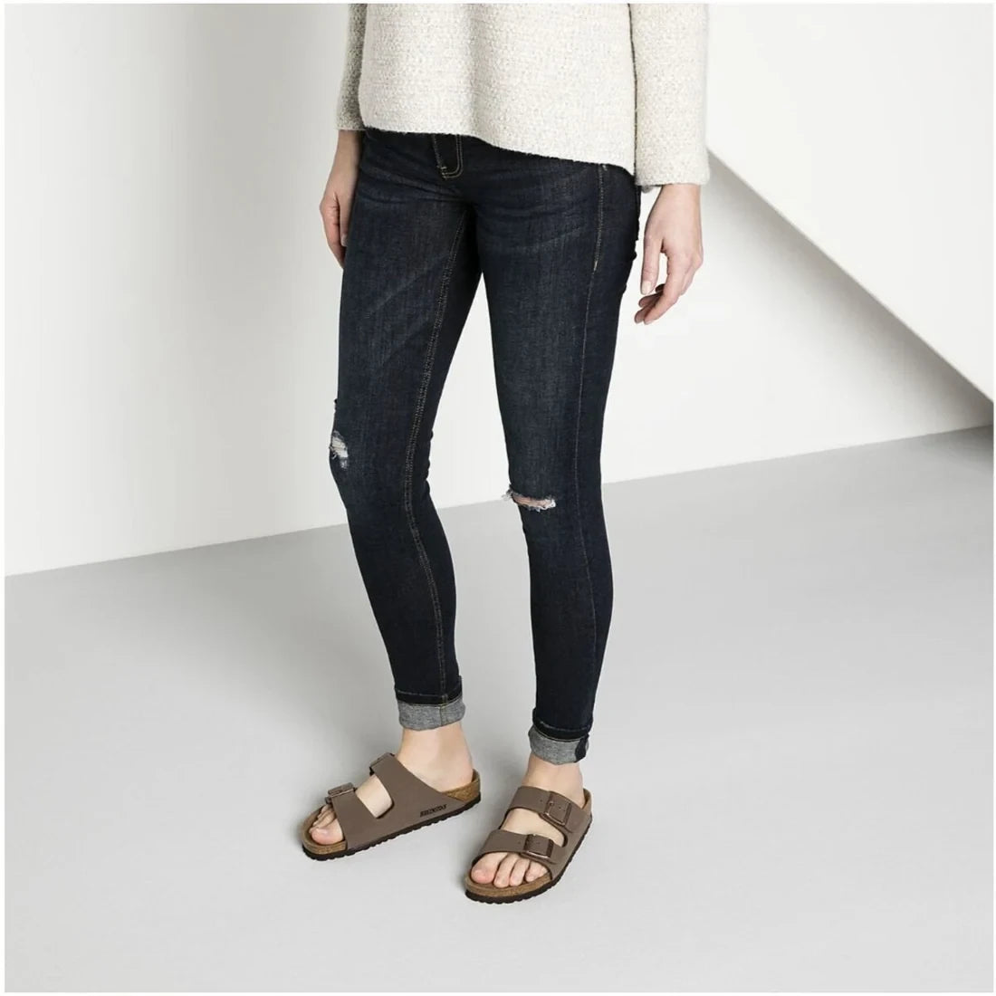 Brown two-strap Birkenstock sandals worn with dark trousers
