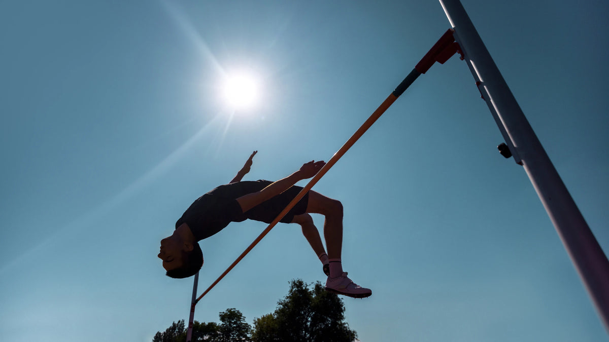 High jumper silhouetted against a blue sky