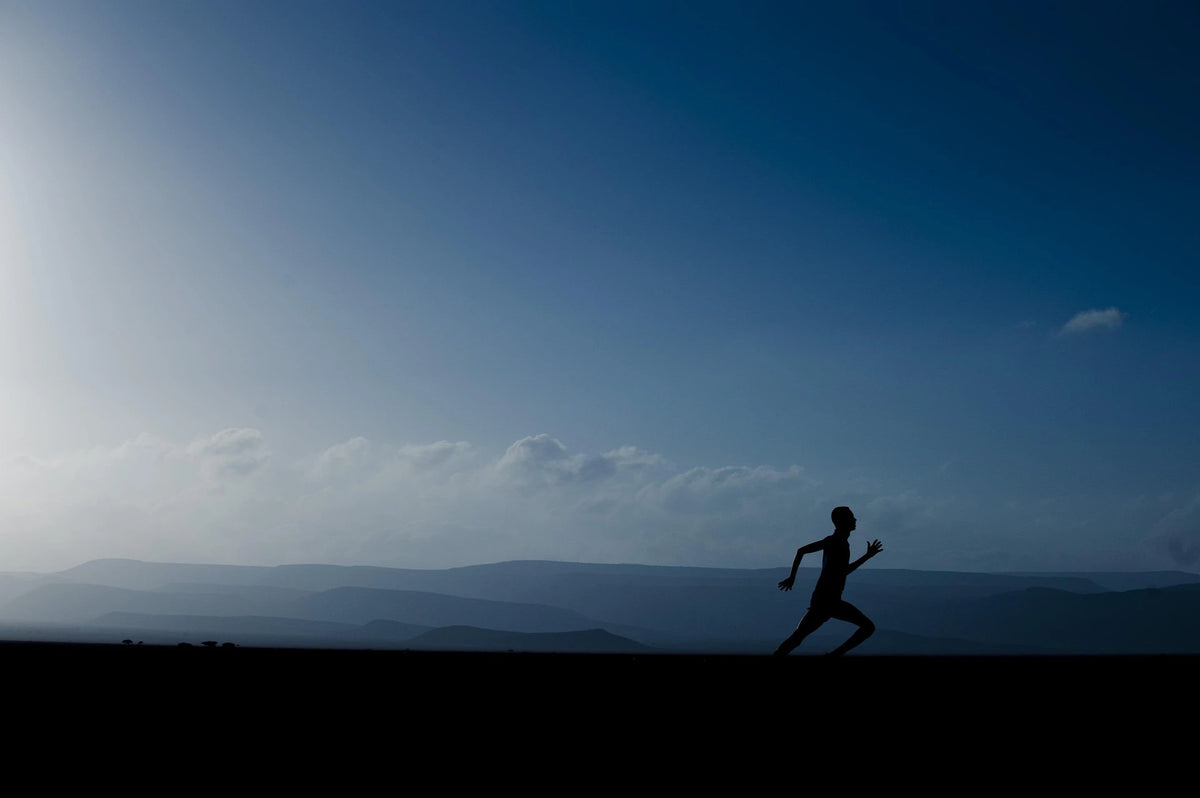 Runner silhouetted against distant hills