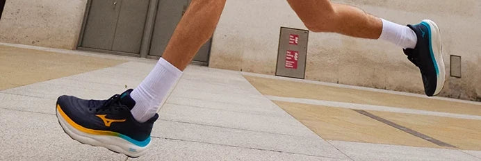 Runner wearing dark Mizuno shoes on pavement