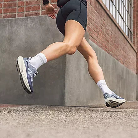 Runner wearing light-coloured shoes beside a brick wall