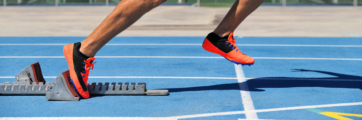 Runner wearing red spikes on a blue athletics track